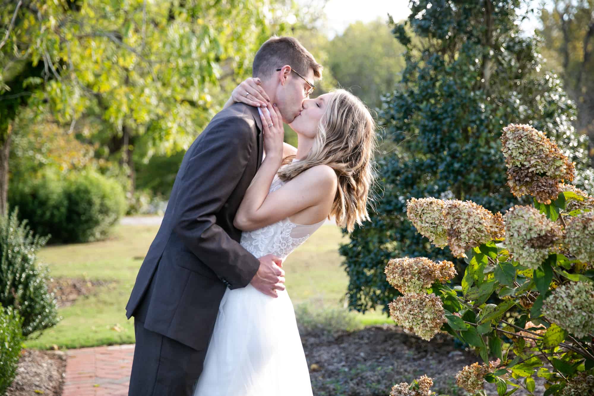 bride and groom kissing among lush greenery at Walnut Hill Raleigh