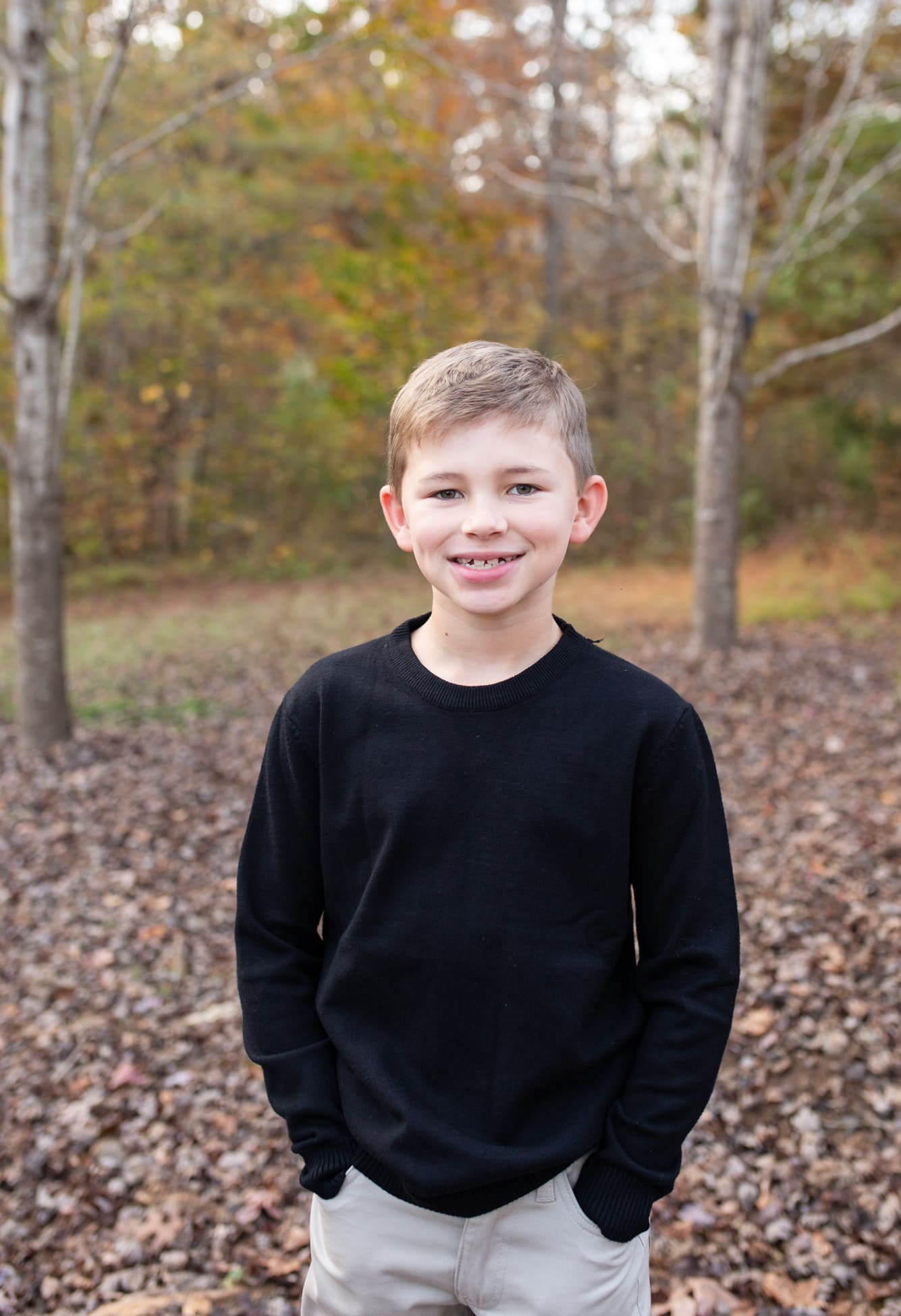 a boy wearing black sweater smiling for the camera