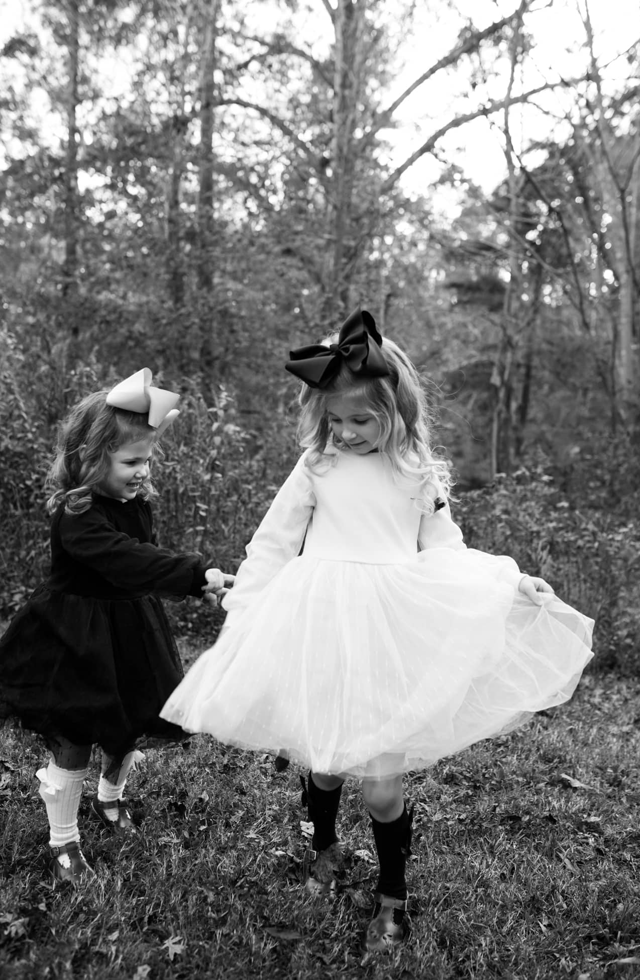 black and white capture of two sisters dancing in a park