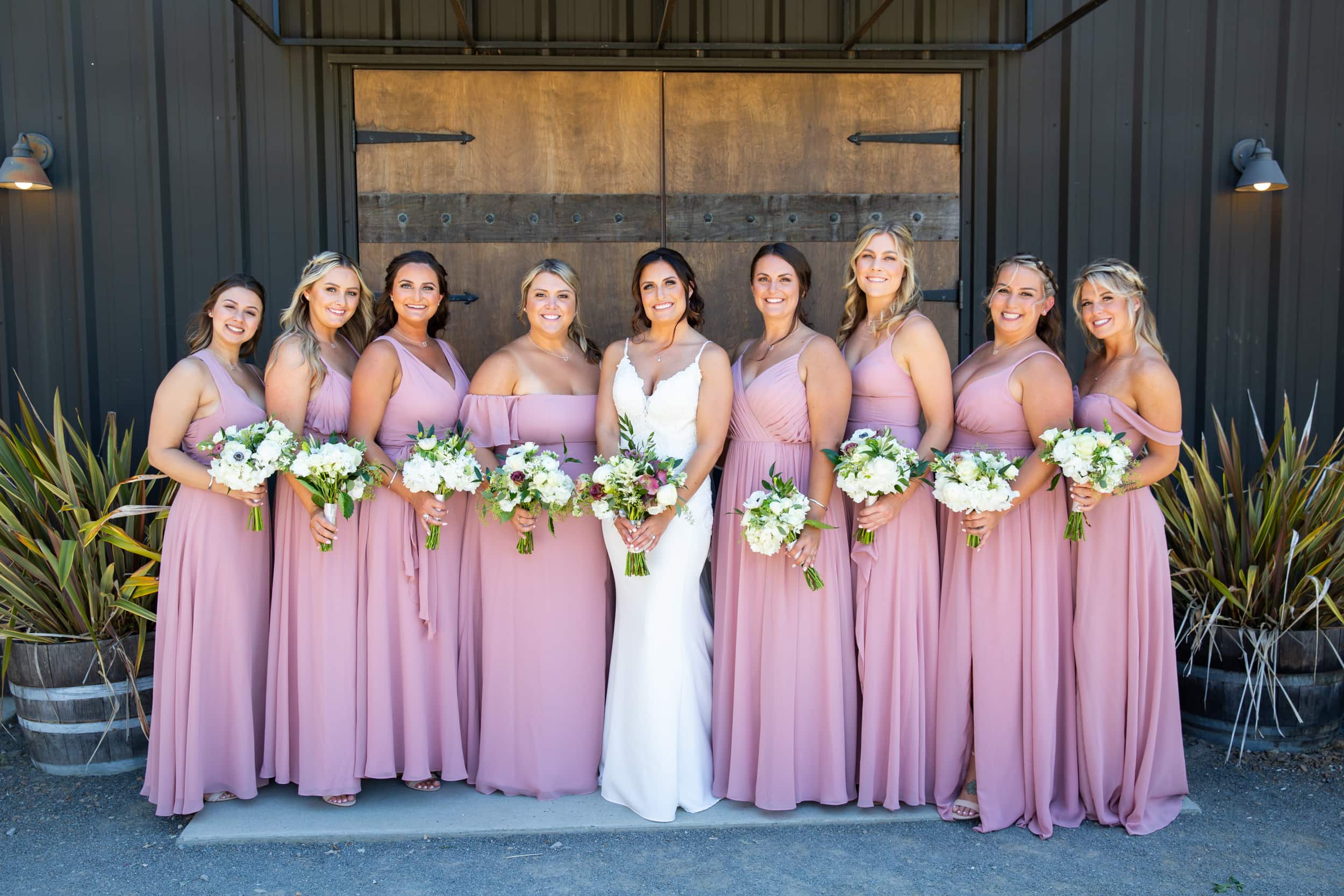 bride and bridesmaids in front of a rustic barn