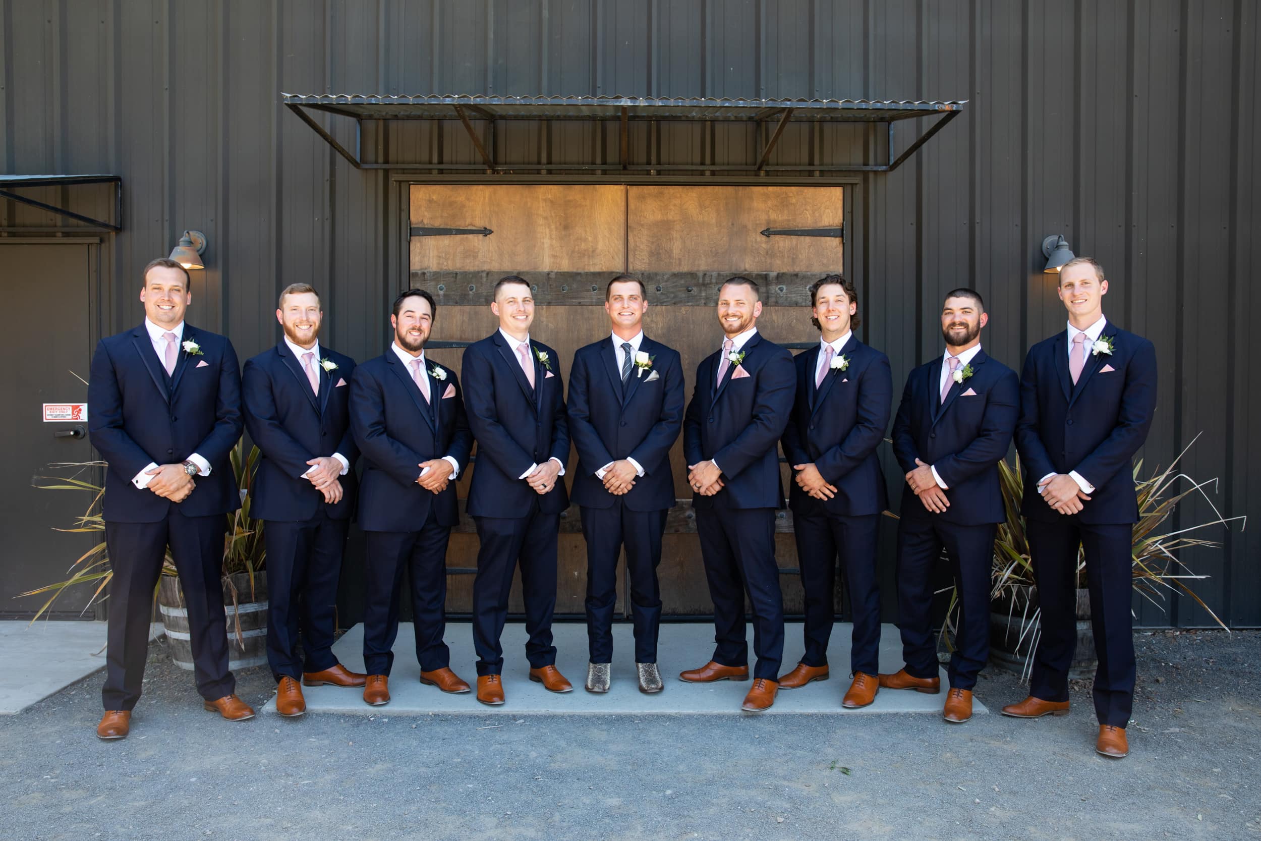 groom and groomsmen in front of a rustic barn