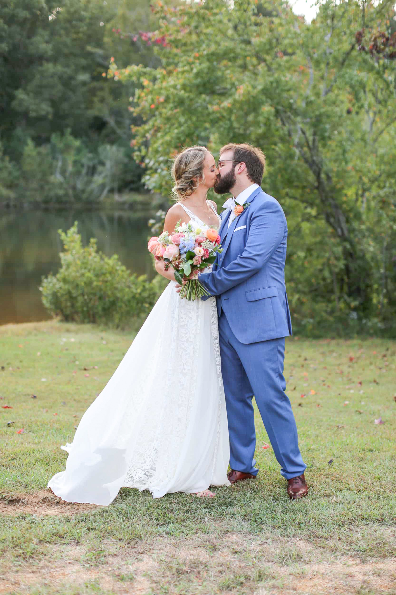 newlyweds kissing by a pond after tying the knot in chapel hill,nc