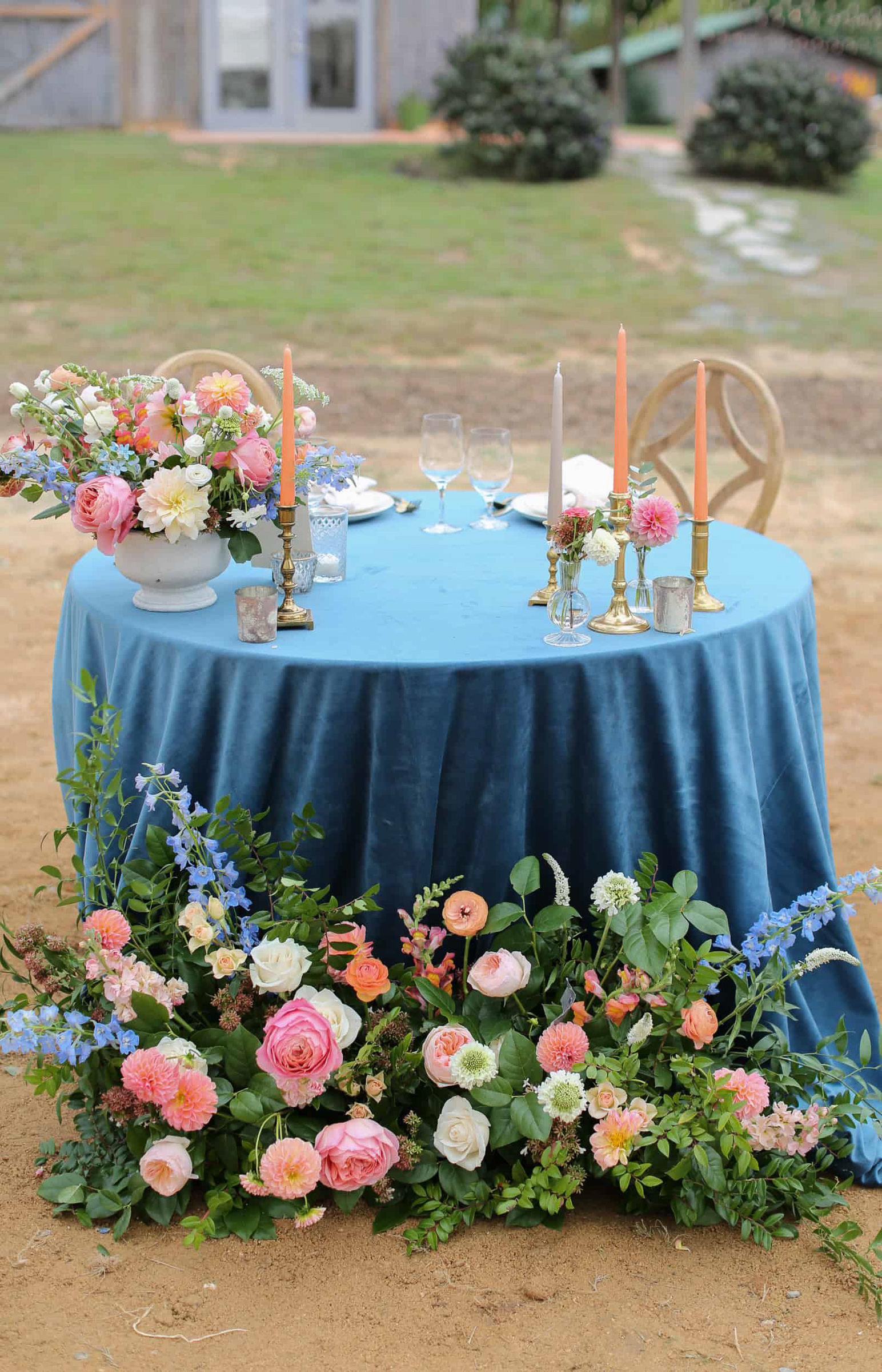 sweetheart table with blue velvet table cloth and orange flower arrangement