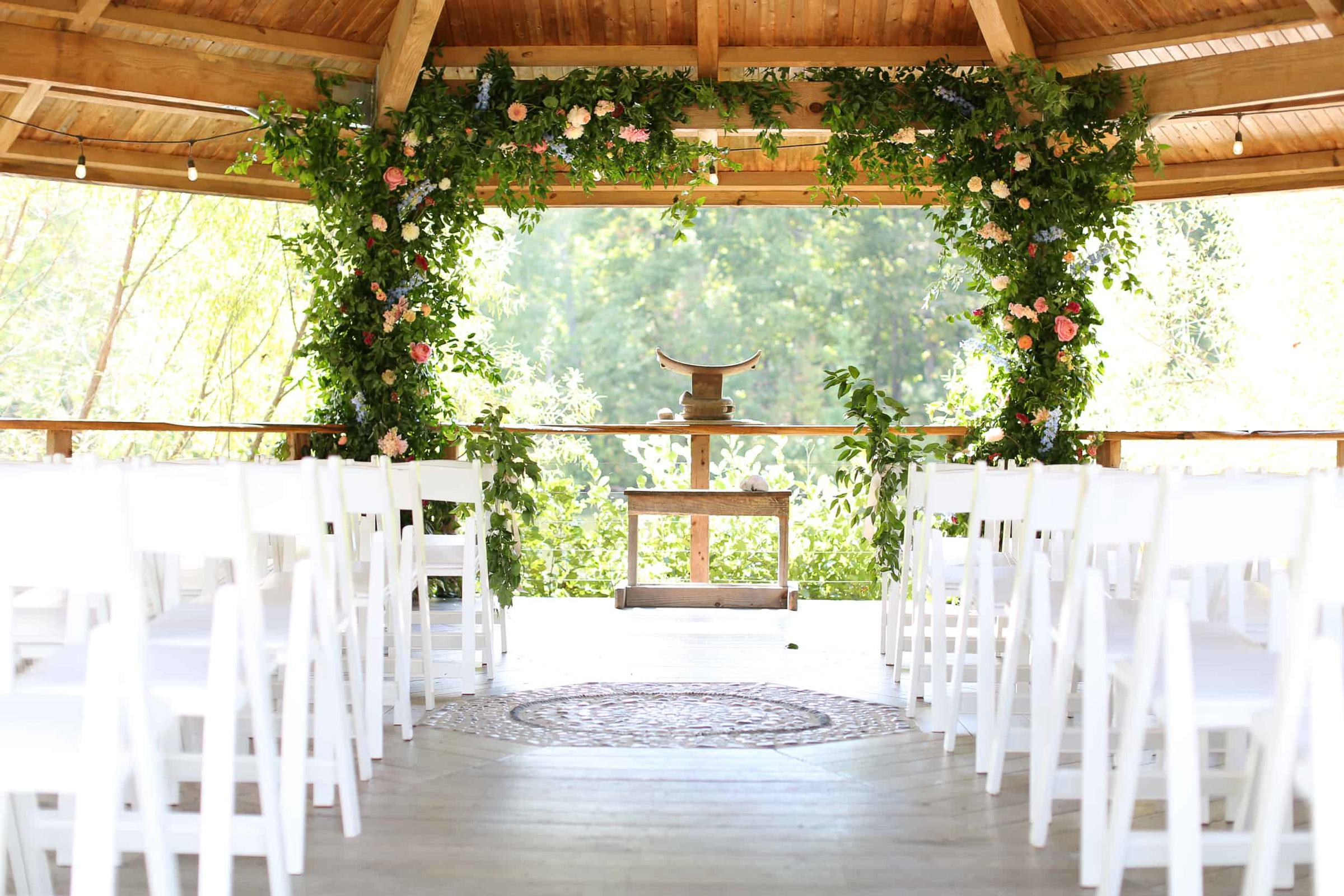 ceremony setup with white chairs and orange and green in a gazebo