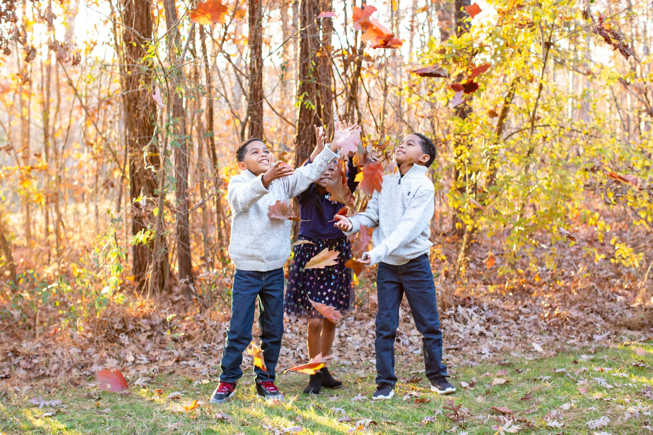 kids playing with leaves during fall family photo session in Raleigh