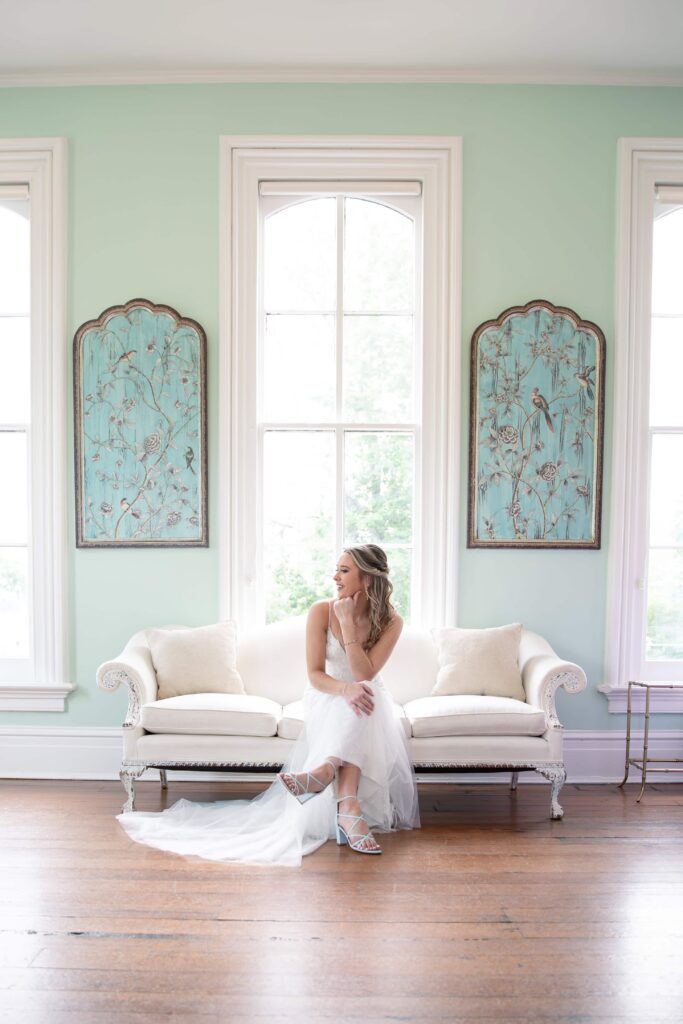 Bride sitting on a vintage sofa at the historic wedding venue downtown Raleigh. Merrimon-Wynne wedding photographer.