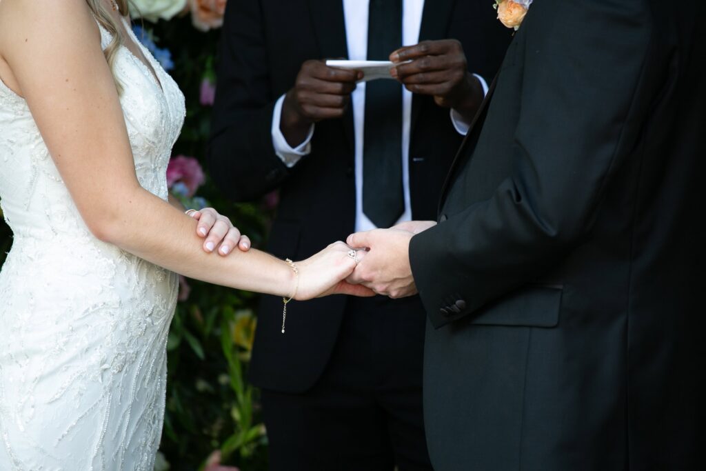 newlyweds holding hands during the ring exchange in a historic wedding venue in Raleigh, NC