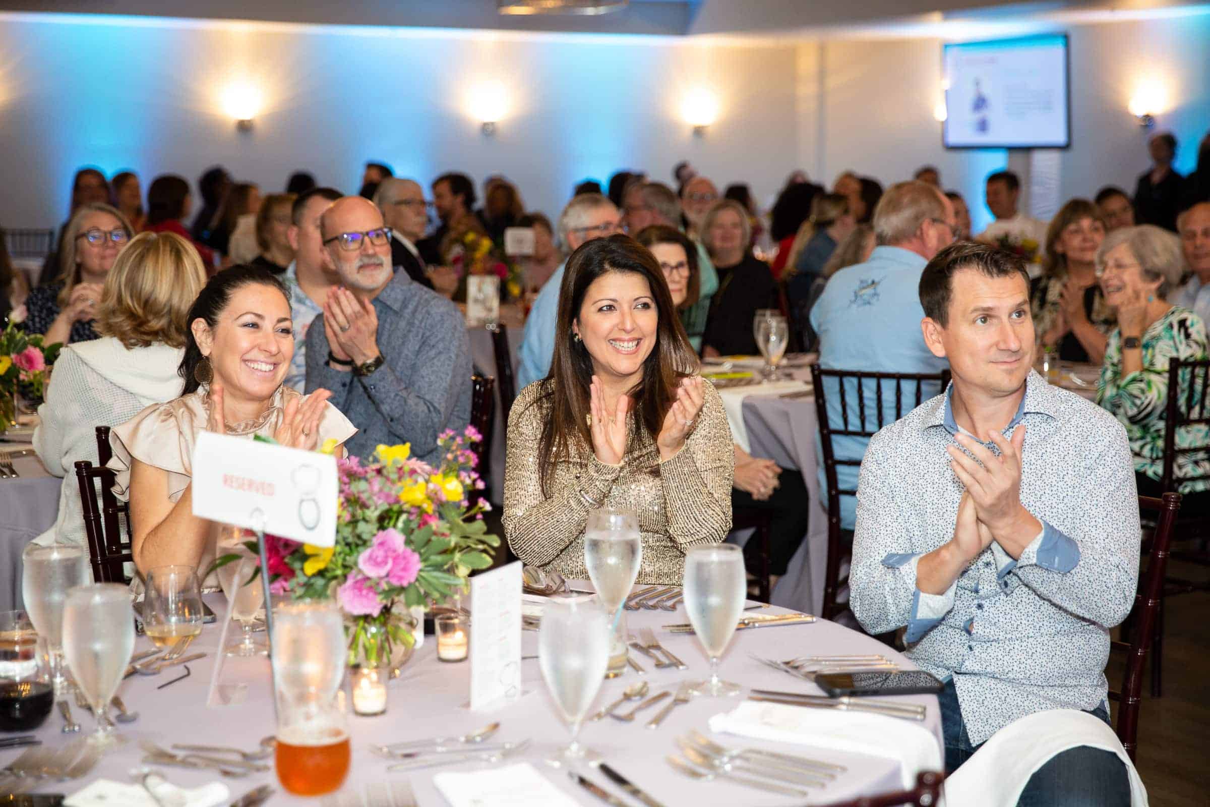 a woman smiling and clapping her hands during a corporate event in Raleigh, NC.