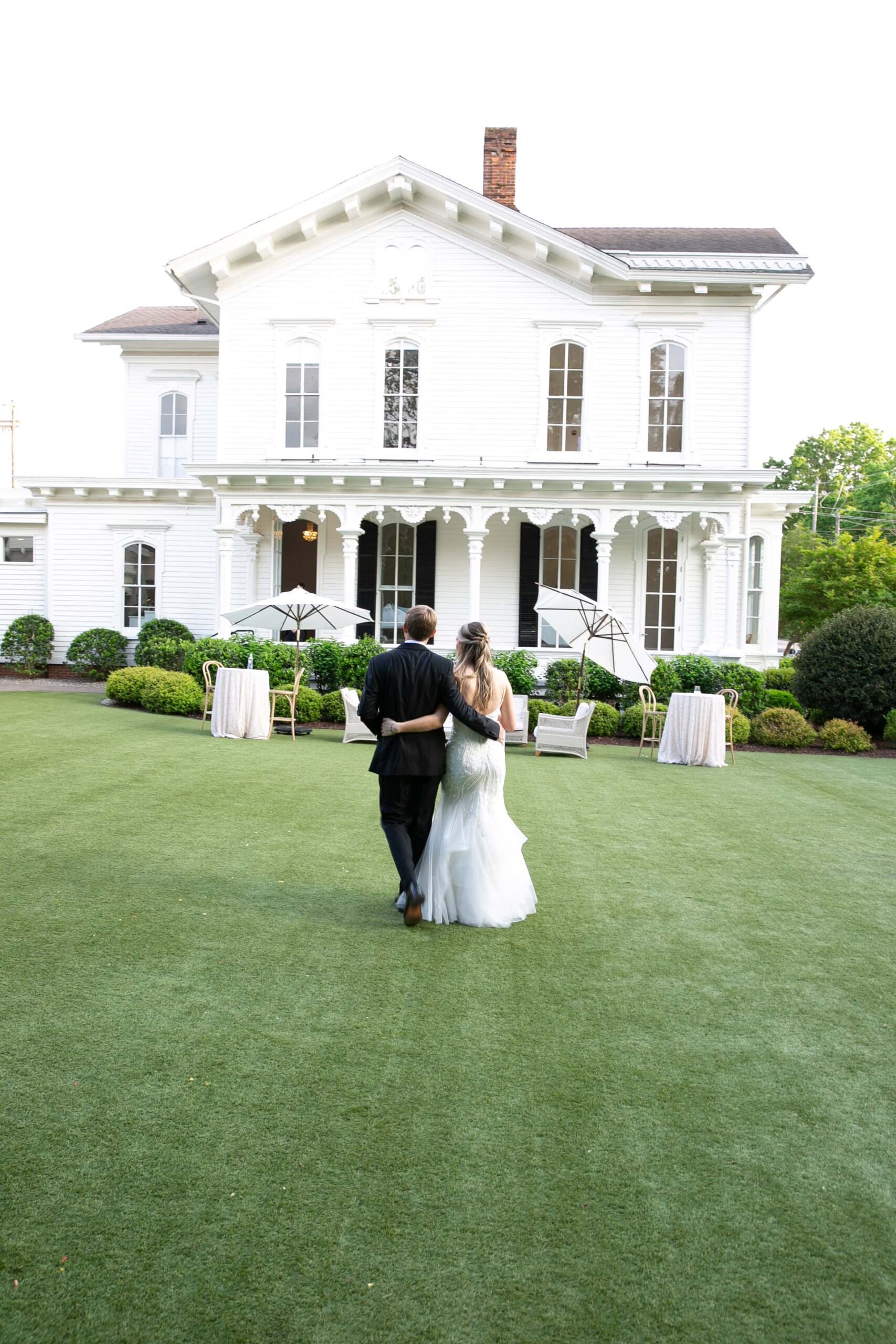 Couple shown during wedding walking towards a white venue building. Finding the Perfect Wedding Photographer in Raleigh NC