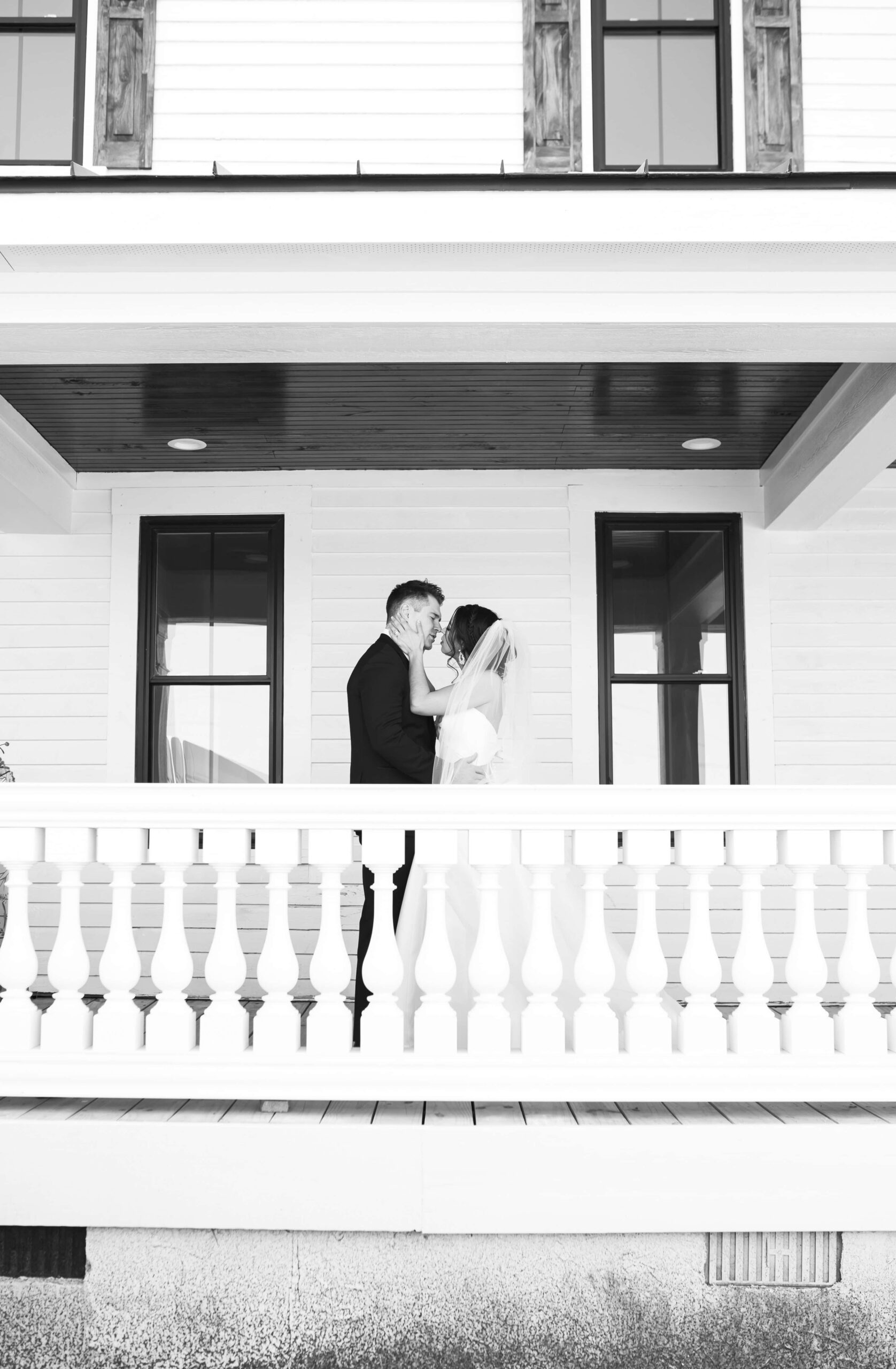 Couple kissing on wrap-around porch of Landon Estate wedding venue in Clayton, NC