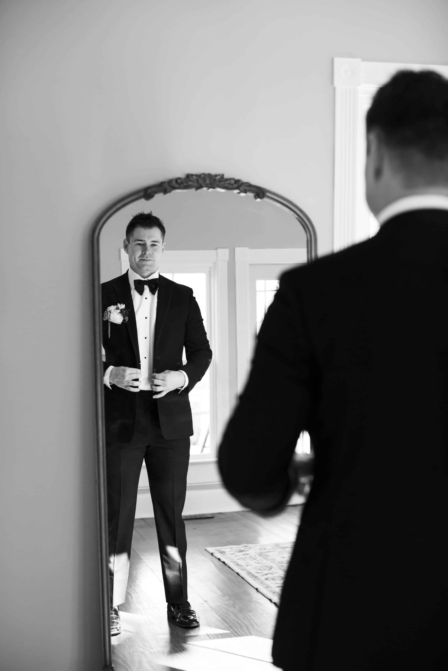 groom getting ready in front of mirror at groom's suite at Landon Estate