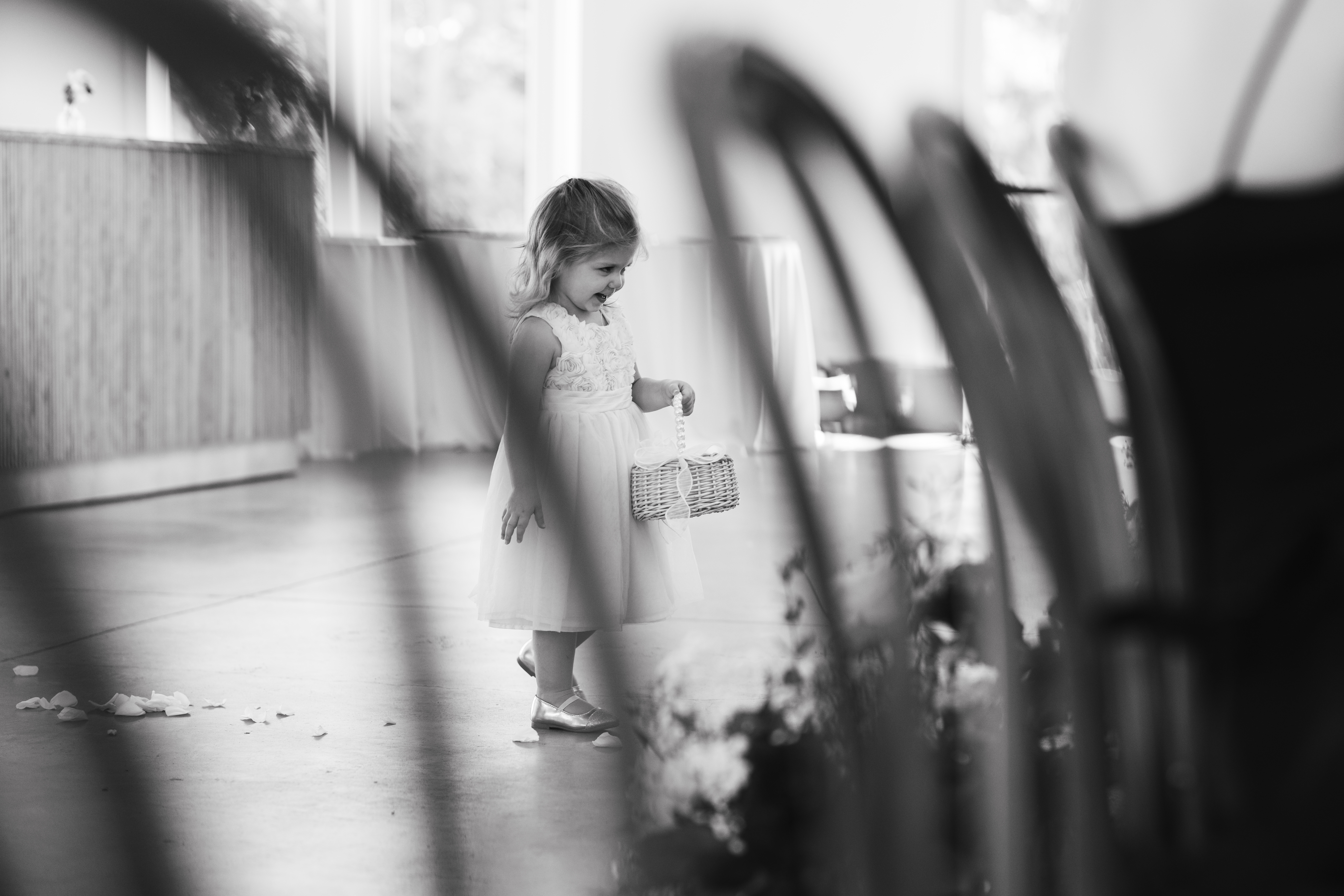 flower girl walking down the aisle with her wooden basket, throwing flower petals.