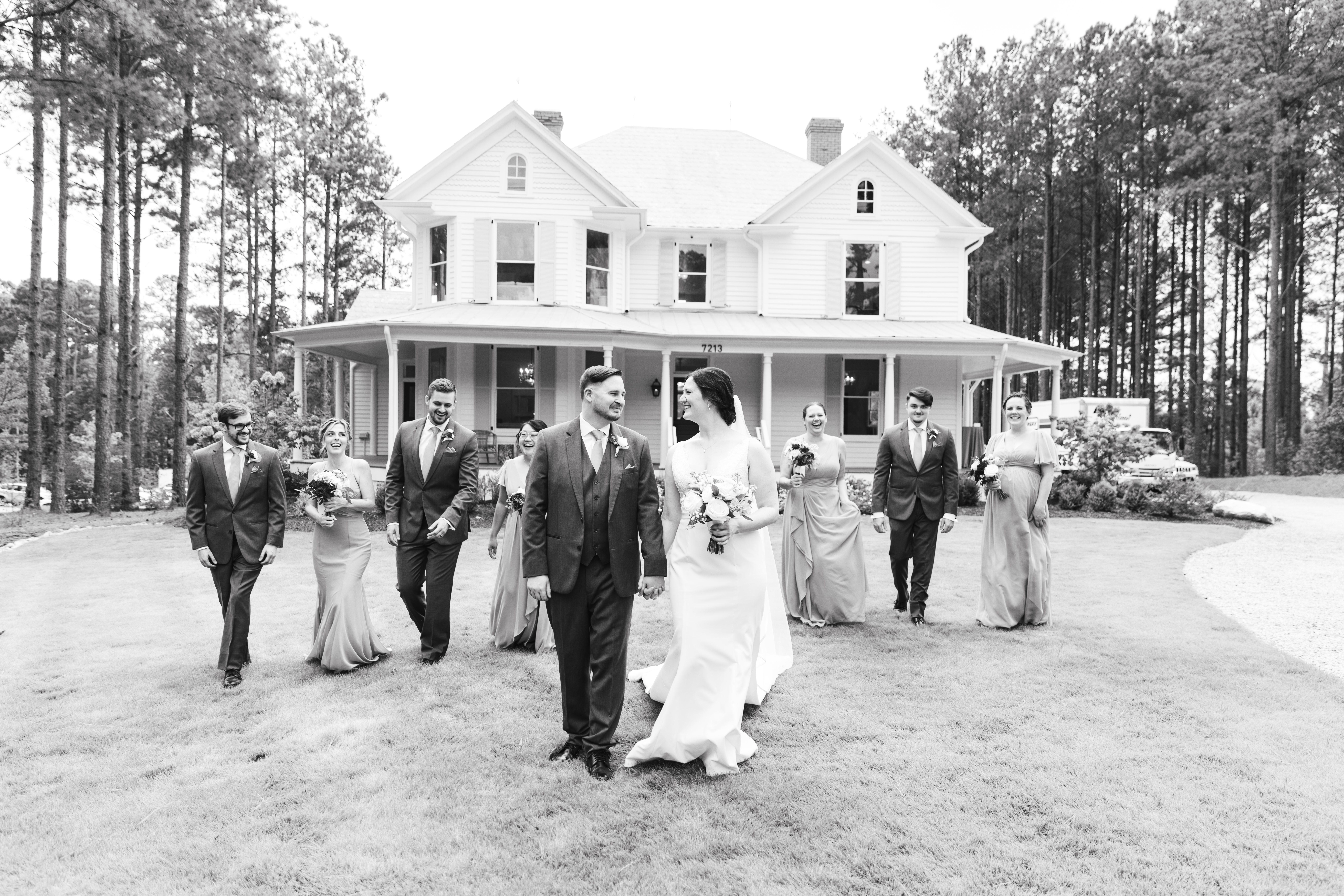 Wedding party walking, laughing and having a good time in front of the historic Upchurch house in Cary, NC.