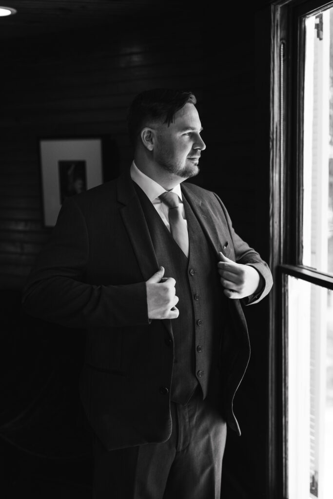 Groom looking outside a window  during getting ready at the historic Upchurch house.