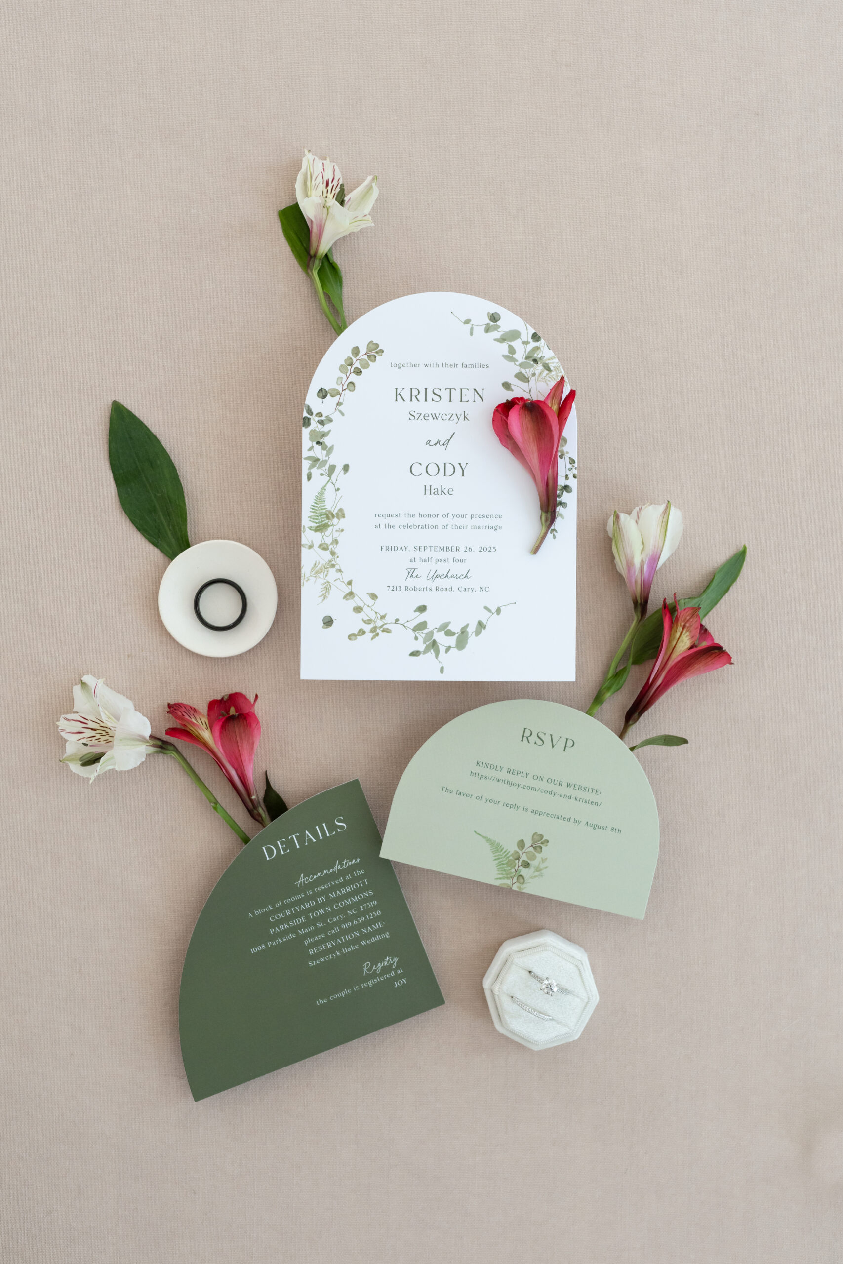 Green wedding invitations arranged with wedding rings and wedding florals. Fall wedding at the Upchurch Cary.