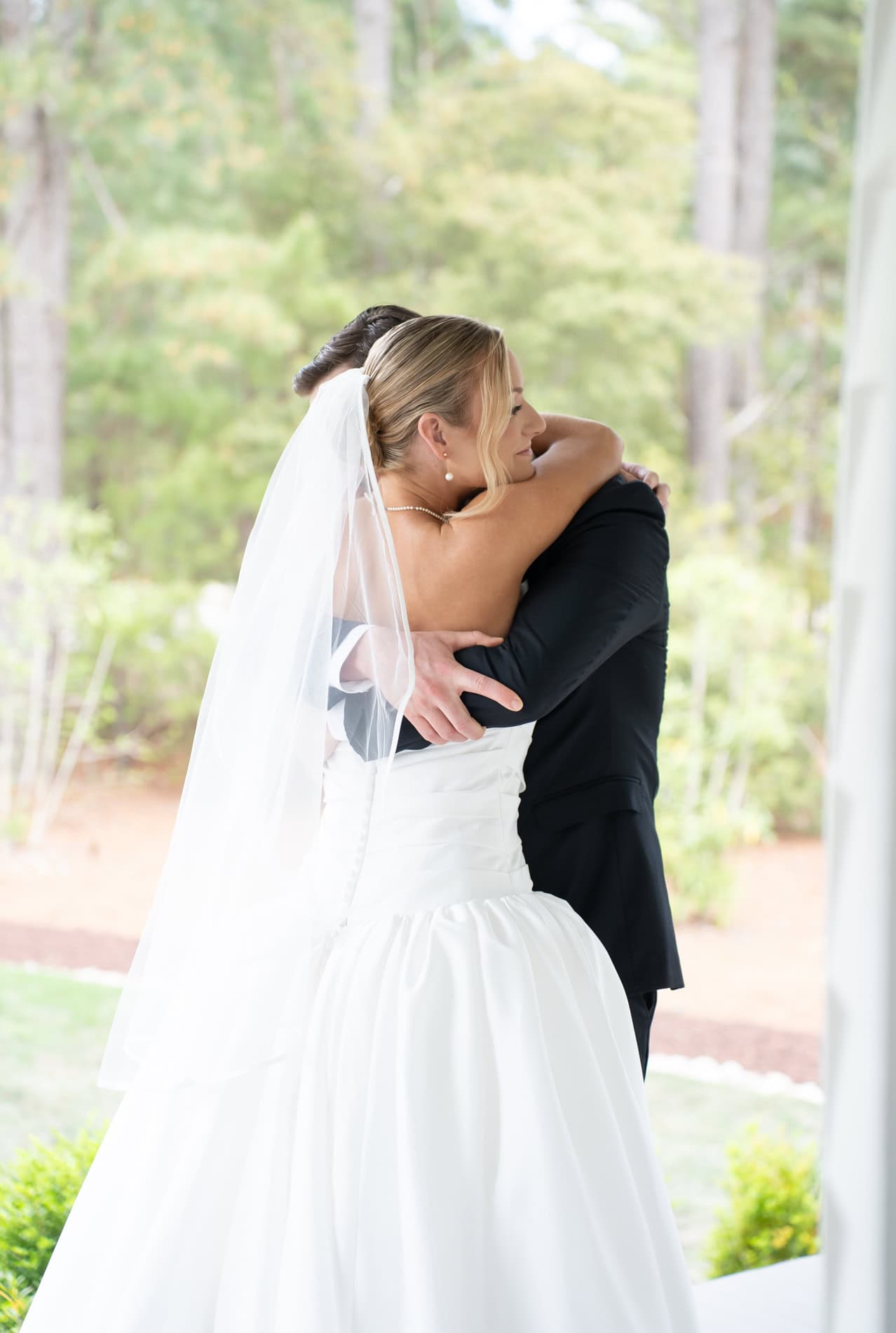 Bride and groom hugging on the porch of the Upchurch. First look between bride and groom-to-be.
