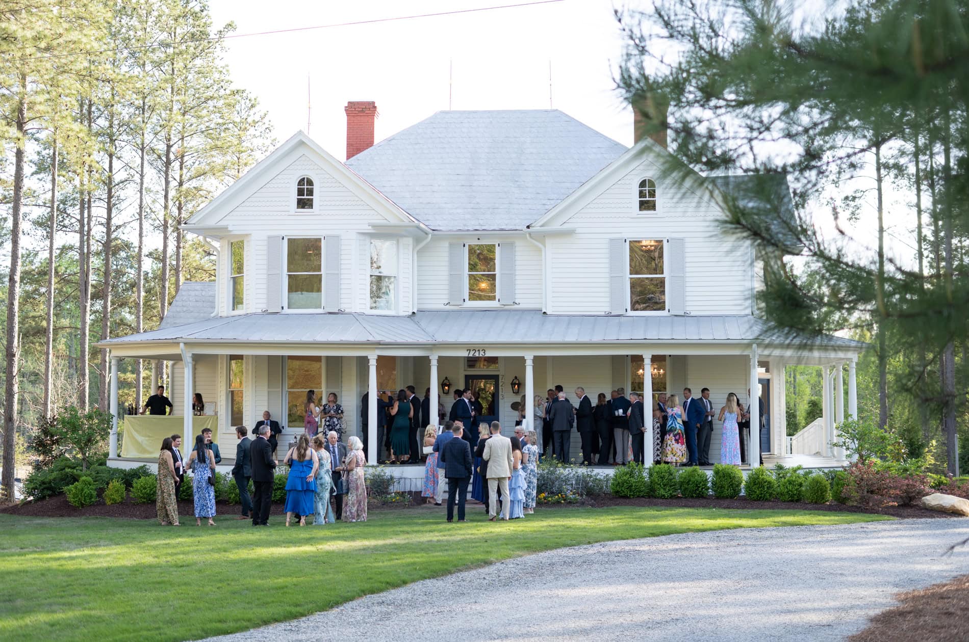 Guests enjoying Cocktail Hour on the porch of the Upchurch historic home. Magdalena Stefanek - The Upchurch wedding photographer.