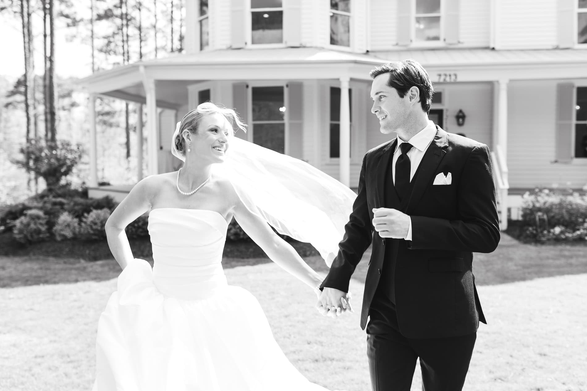 bride and groom running in front of the upchurch historic home in Cary,NC by raleigh wedding photographer.