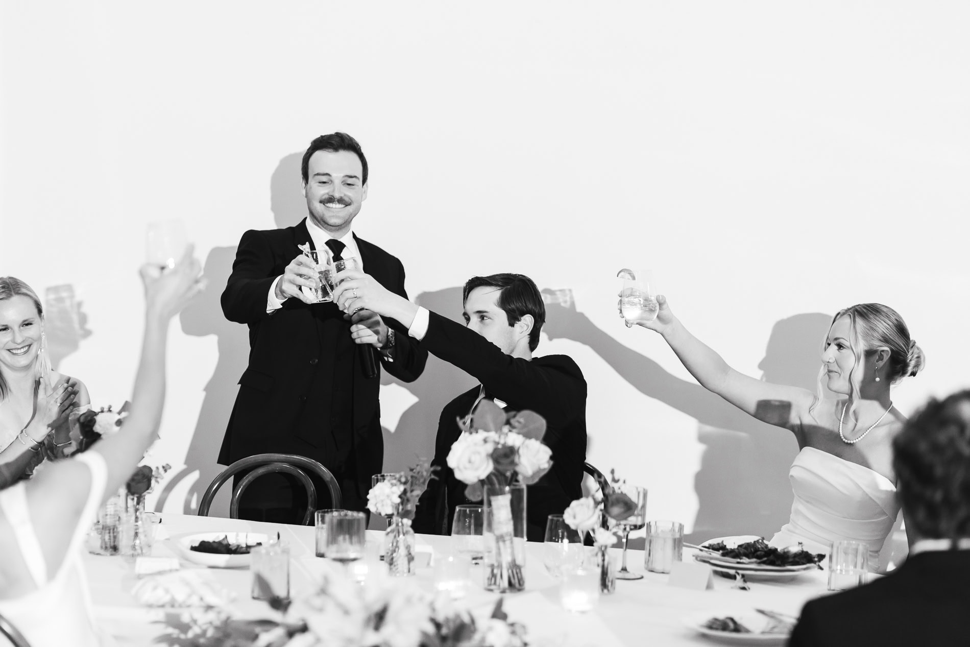 Bride and Groom clinging glasses with Wedding party after best man's toast
